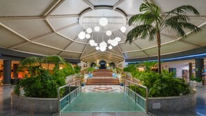 A spacious atrium with a central staircase, surrounded by lush greenery and modern lighting fixtures. - Relaxia Lanzasur- All Inclusive (Yaiza)