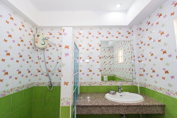A bathroom with a shower, a sink, and a mirror. The walls are tiled with a floral pattern. - De Lunar Resort Koh Larn (Koh Lan)