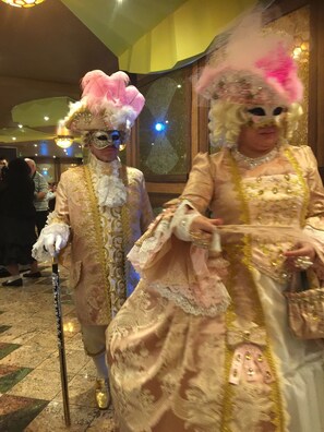 Two individuals in elaborate costumes with a checkered floor and a chandelier in the background. - Danescourt Lodge (Blackpool)