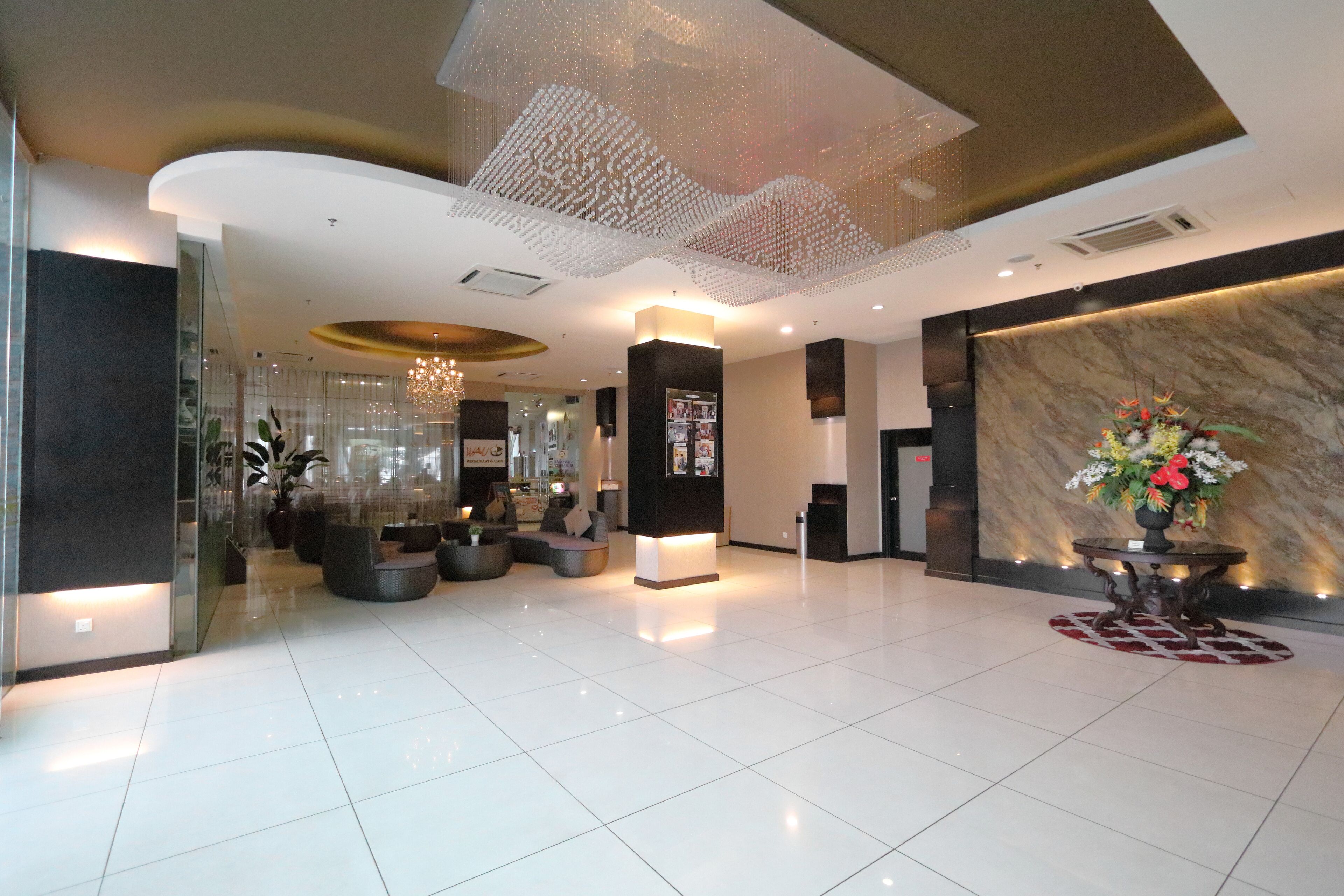 A modern lobby with a marble reception desk, seating area, and decorative ceiling.