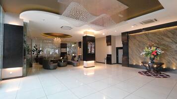 A modern lobby with a marble reception desk, seating area, and decorative ceiling.