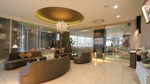 A modern lobby with a reception desk, seating area, and a chandelier. - The Guest Hotel & Spa (Port Dickson)