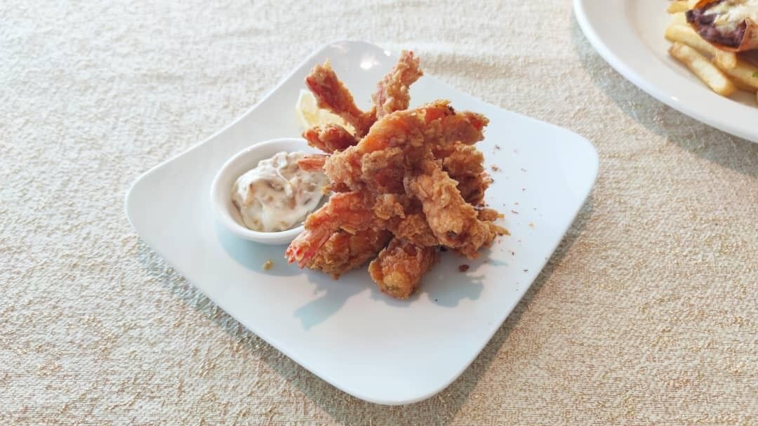 Un plato blanco con pollo frito y un recipiente pequeño de salsa.