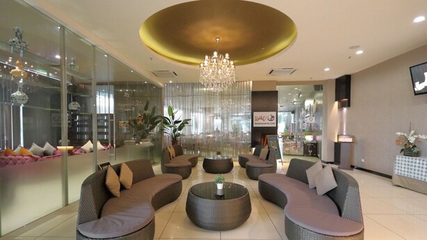 A modern lounge area with wicker sofas, a central coffee table, and a chandelier. - The Guest Hotel & Spa (Port Dickson)