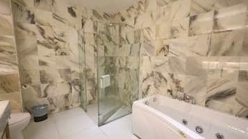 A modern bathroom with a glass-enclosed shower, a white bathtub, and marble-patterned walls.