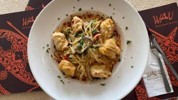 Un plat de pâtes au poulet et aux légumes, posé sur une table avec une serviette et un menu.