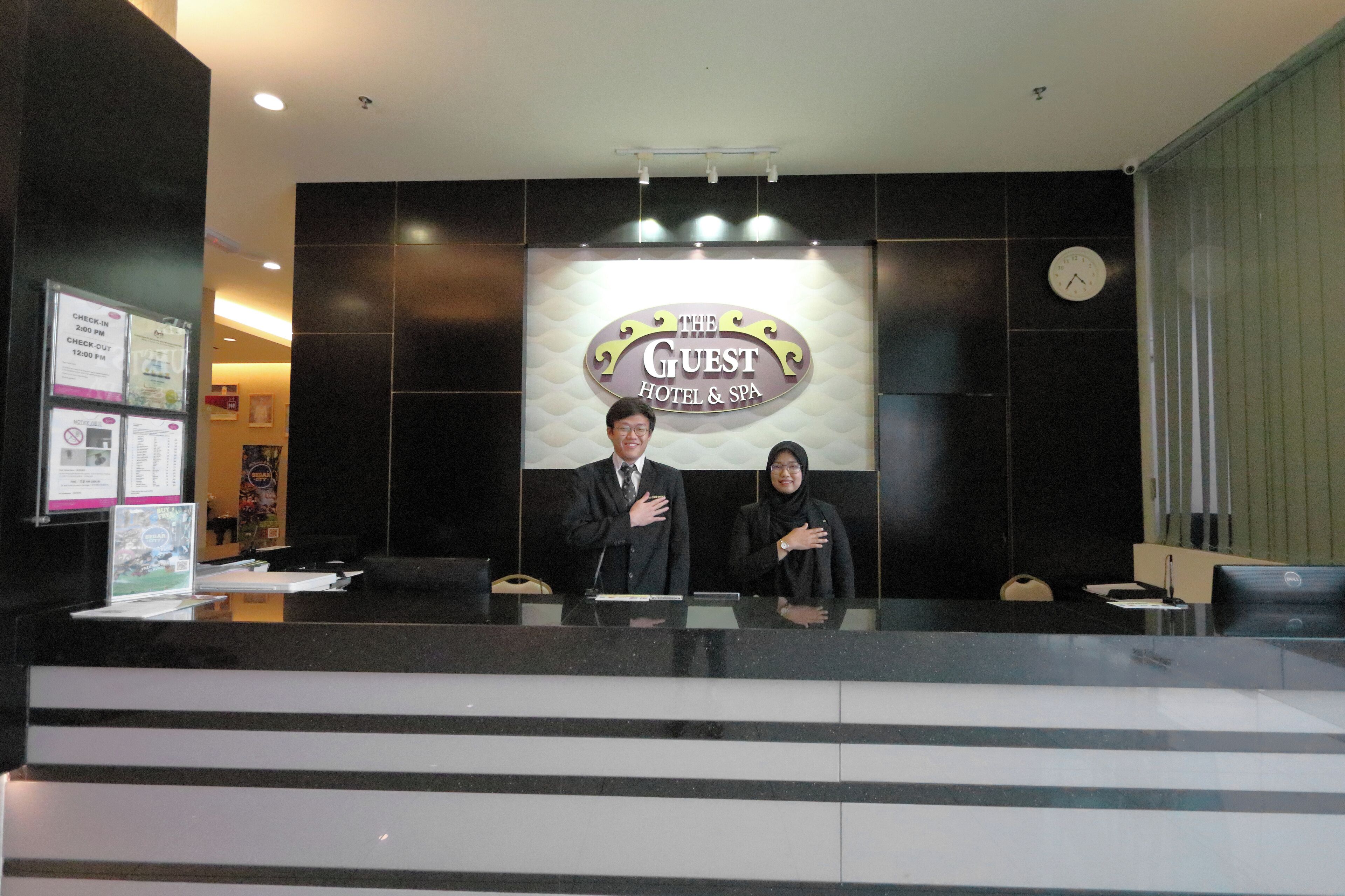 A reception desk at The Guest Hotel & Spa with a large sign above.