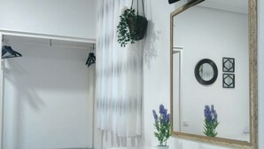 A room with a white desk, chairs, a television, a mirror, and a hanging plant. - Hostal Bruña (Madrid)