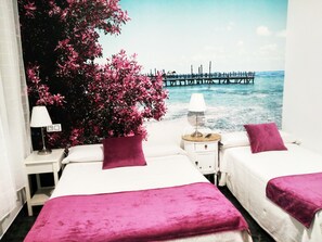 A hotel room with two beds, a nightstand with a lamp, and a view of a pier over water. - Hostal Bruña (Madrid)