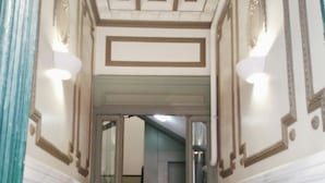 A hallway with a marble floor, a door with glass panels, and a staircase in the background. - Hostal Bruña (Madrid)