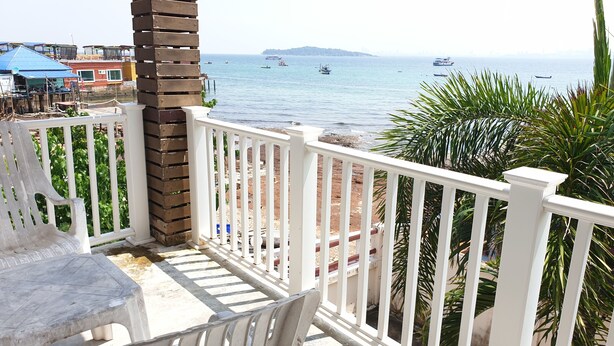 A balcony with a view of the sea, a white railing, and a table with chairs. - Sea Beach Koh Larn 2 (Koh Lan)