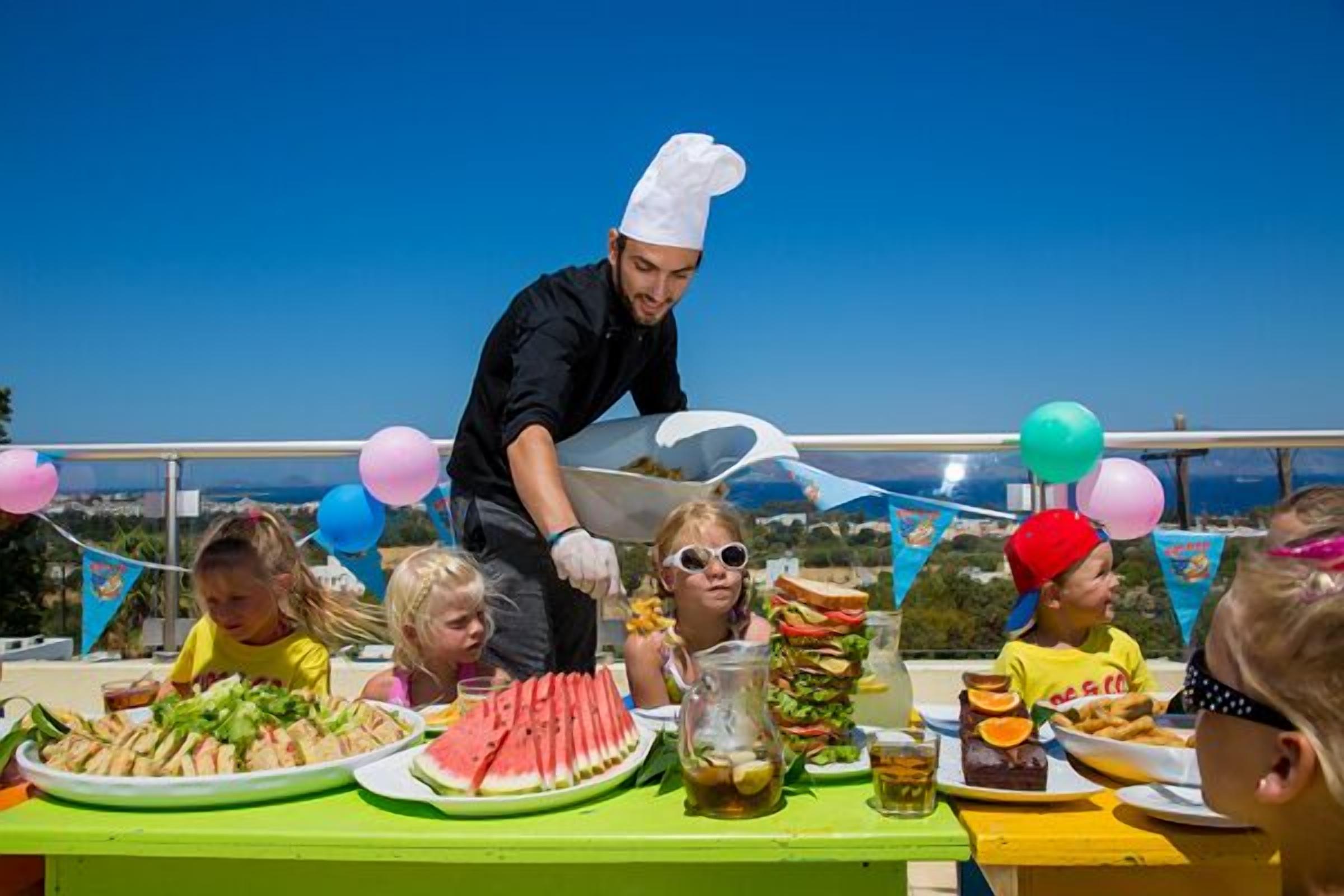 A chef serving food at an outdoor event with a clear view of the sea in the background.
