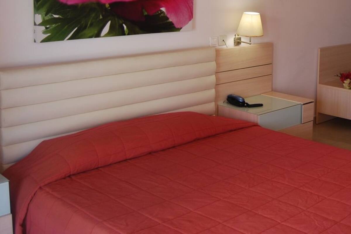 A neatly arranged bedroom with a bed, bedside tables, a nightstand, and a small dresser.
