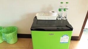 A green refrigerator with a black top, a white basket, and two bottles of water. - Sea Beach Koh Larn 3 (Koh Lan)