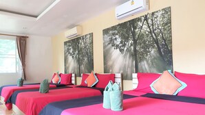 A hotel room with three beds, each with red and blue bedding, and matching pillows. There are two large forest-themed wall art pieces above the beds. - Sea Beach Koh Larn 3 (Koh Lan)