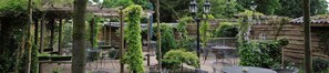 Un patio al aire libre con pérgolas de madera, mesas y sillas.