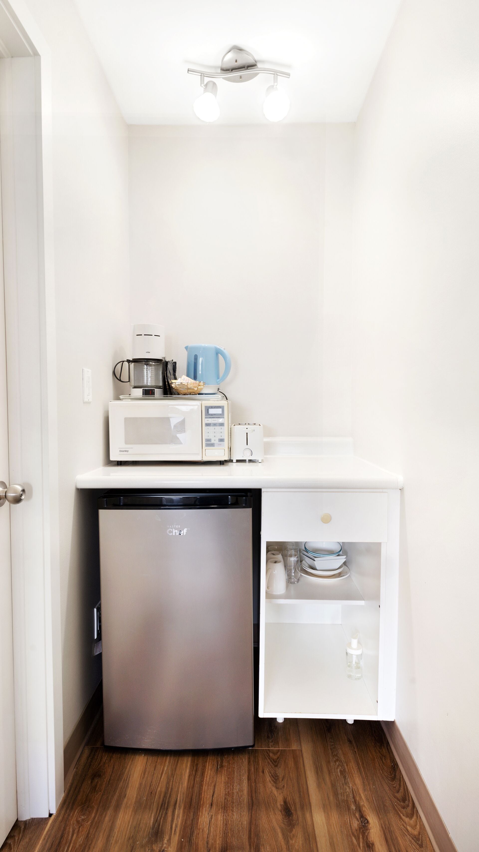 A compact kitchen with a refrigerator, microwave, toaster, and coffee maker.