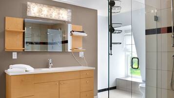 Een moderne badkamer met een douchecabine van glas, een houten wastafelmeubel met een spiegel, en uitzicht op de natuur.