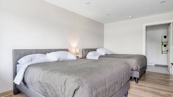 Une chambre d’hôtel moderne avec deux lits, un plancher en bois et un mur blanc.