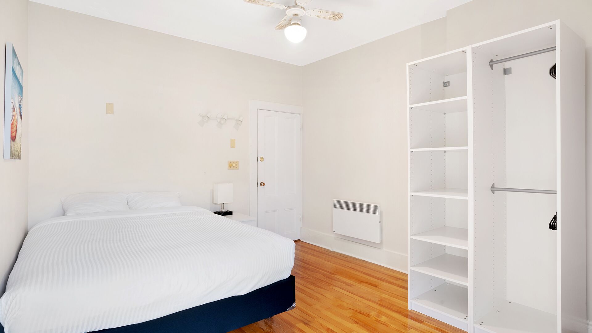 A bedroom with a bed, a wardrobe, a radiator, and a ceiling fan.