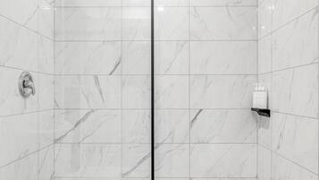 A modern bathroom with a shower, toilet, and tiled floor.