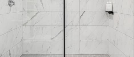 A modern bathroom with a shower, toilet, and tiled floor.
