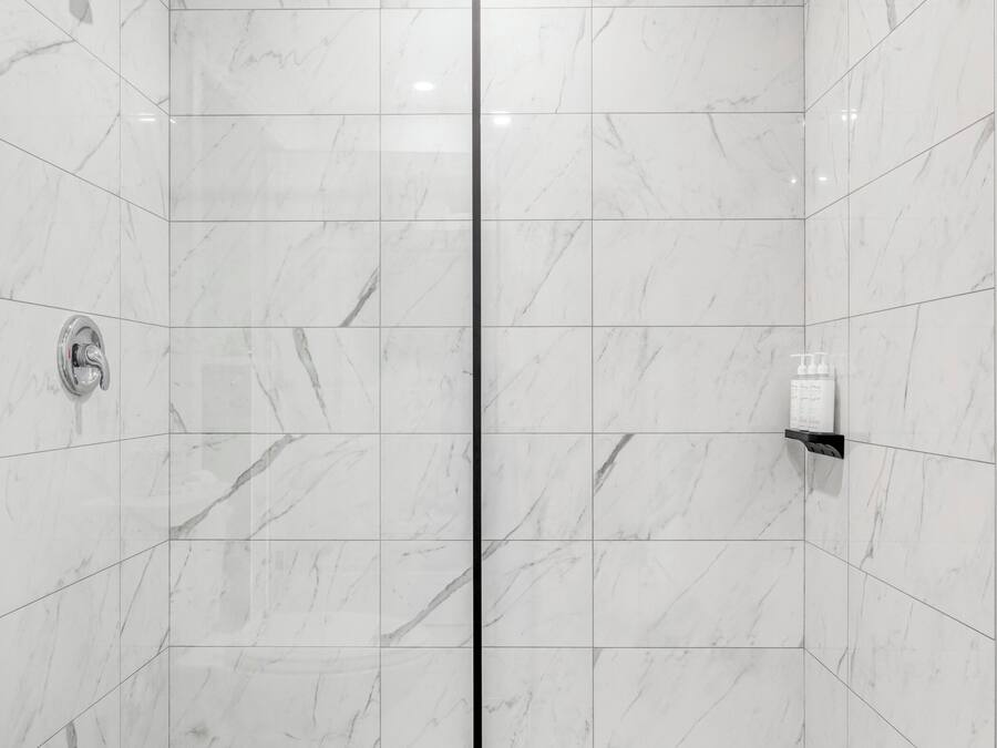 A modern bathroom with a shower, toilet, and tiled floor.