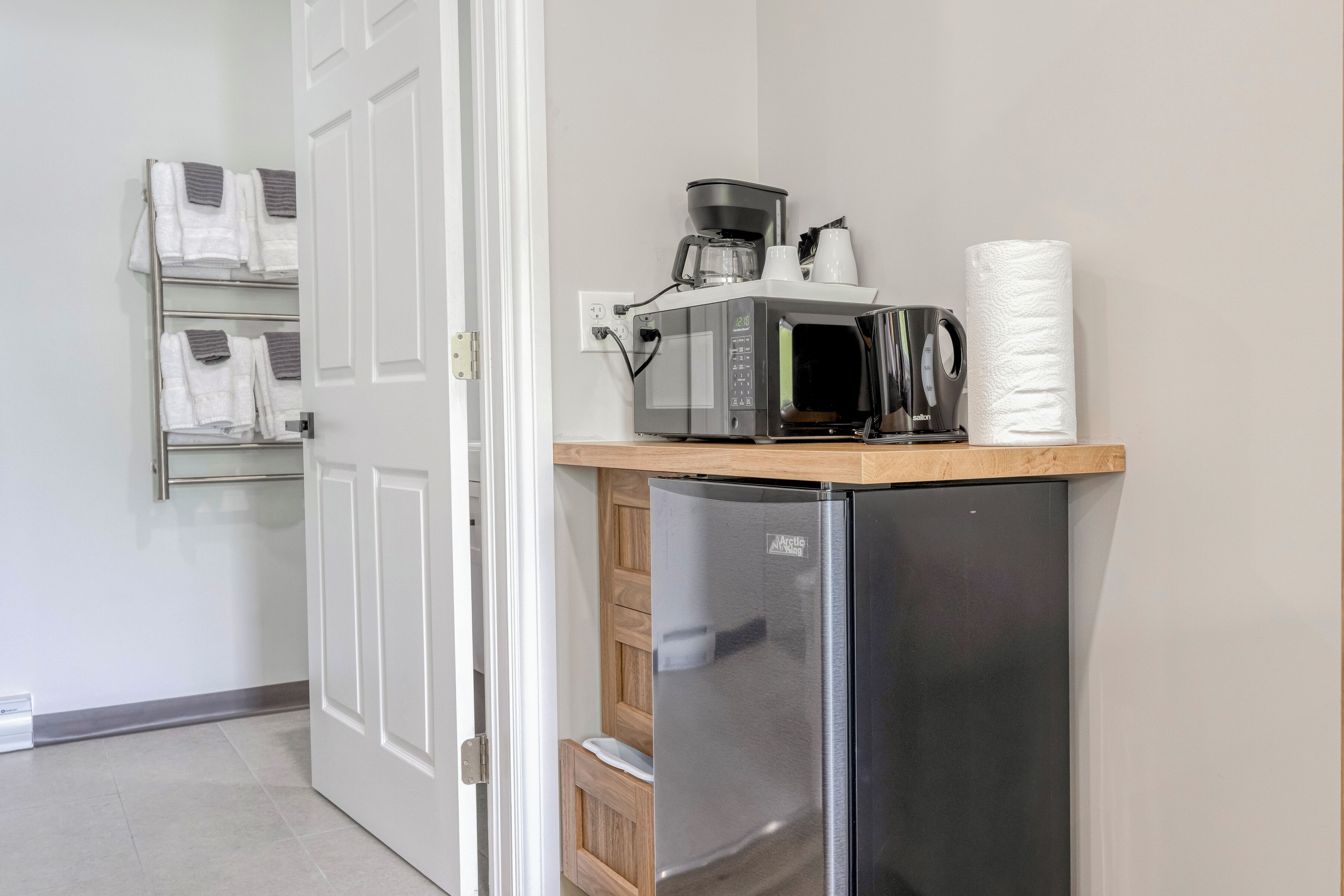 A compact kitchen with a refrigerator, microwave, coffee maker, and paper towels.