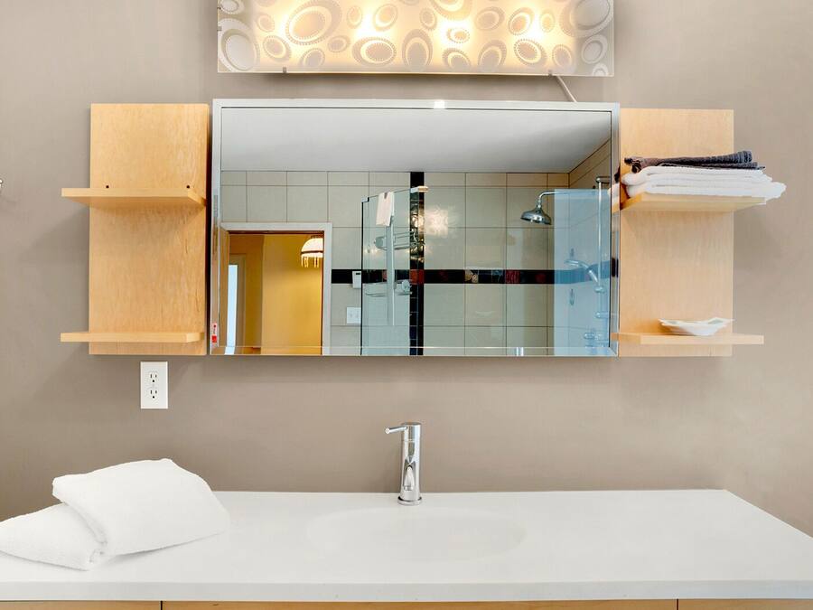 Een moderne badkamer met een witte wastafel, een spiegel erboven en houten planken aan weerszijden.