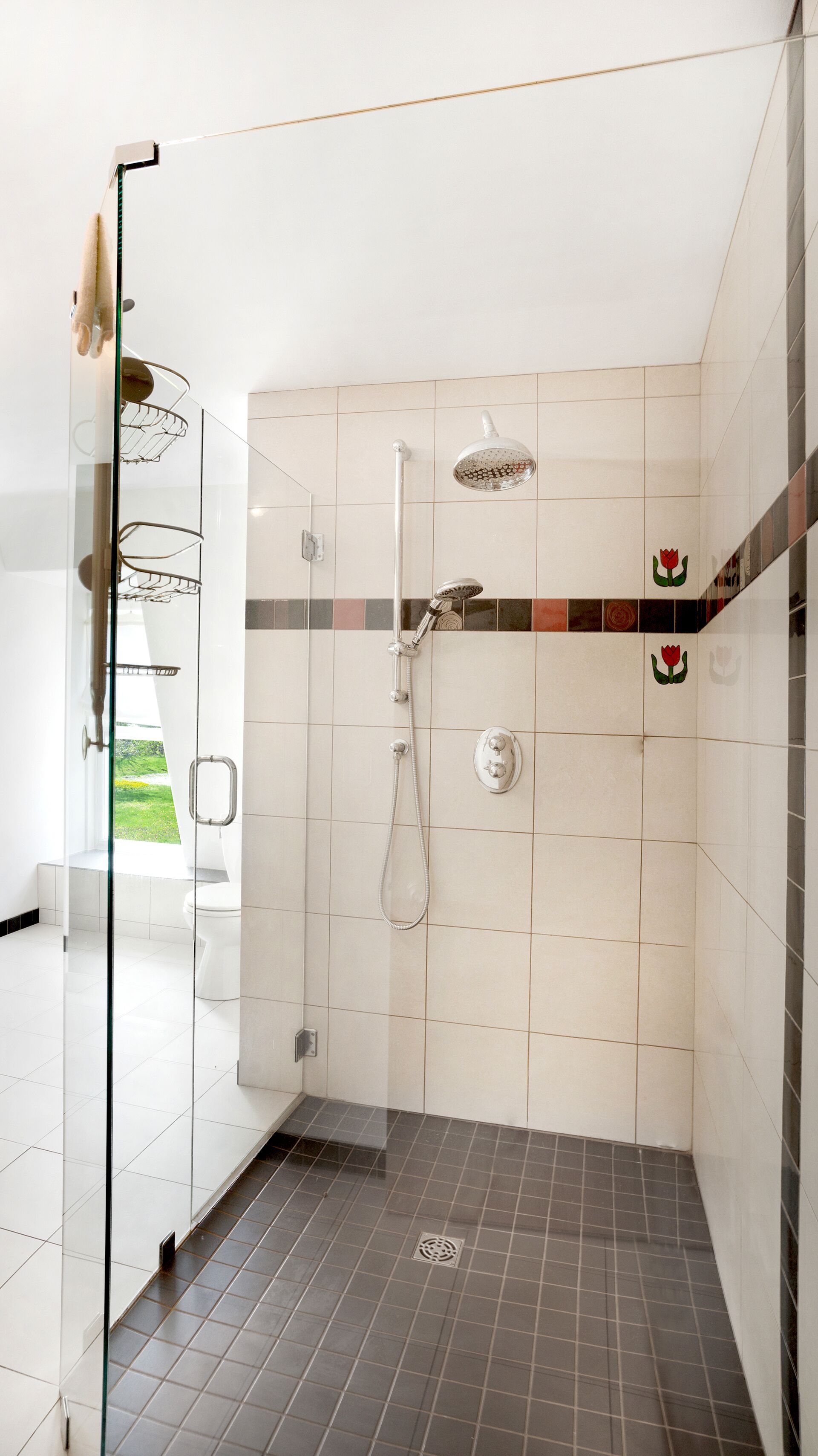 Un baño moderno con cabina de ducha de vidrio, ducha de mano, grifo empotrado en la pared y un inodoro.