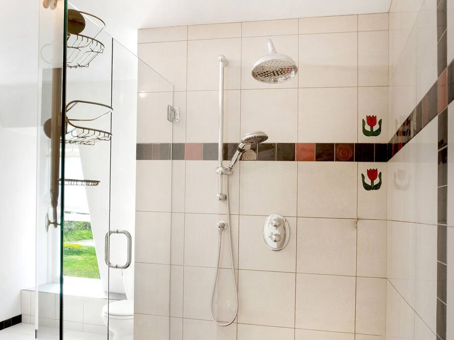 A modern bathroom with a glass shower enclosure, a handheld showerhead, a wall-mounted faucet, and a toilet.