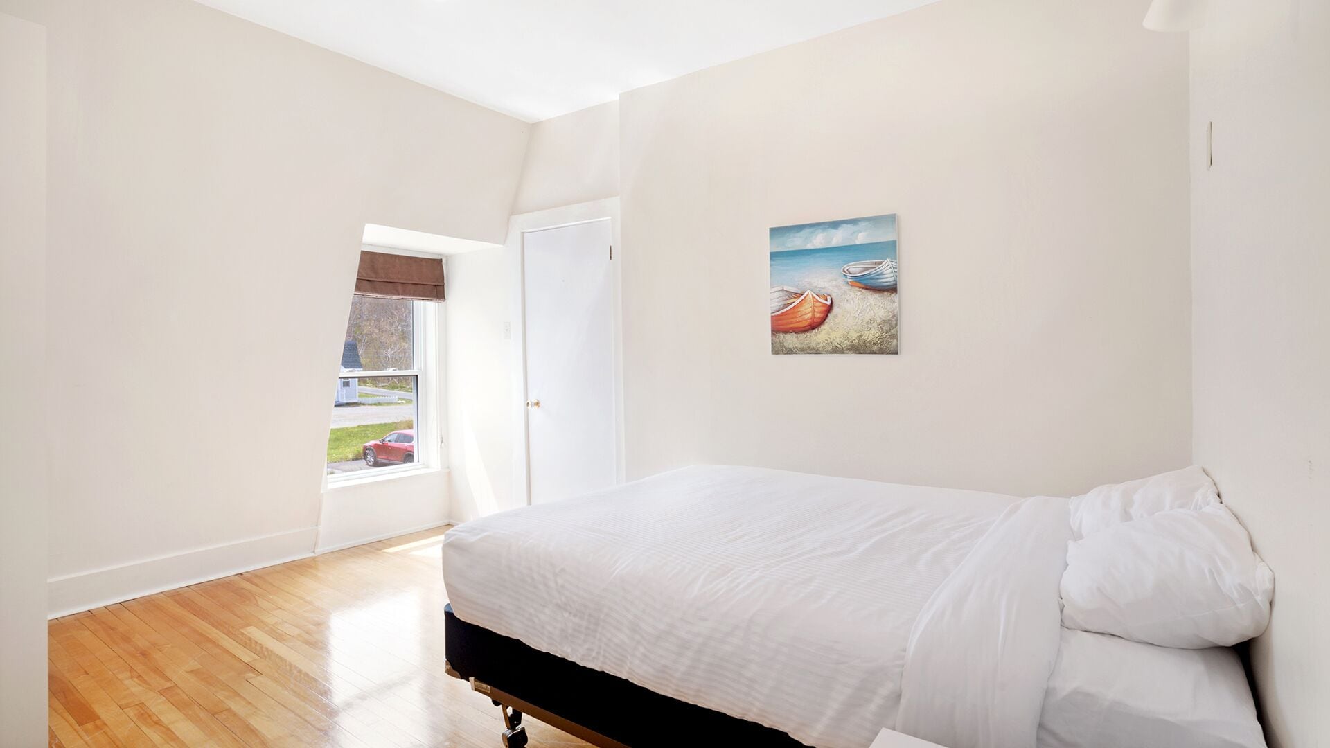 Une chambre à coucher avec un lit, une fenêtre, une porte et un tableau au mur.