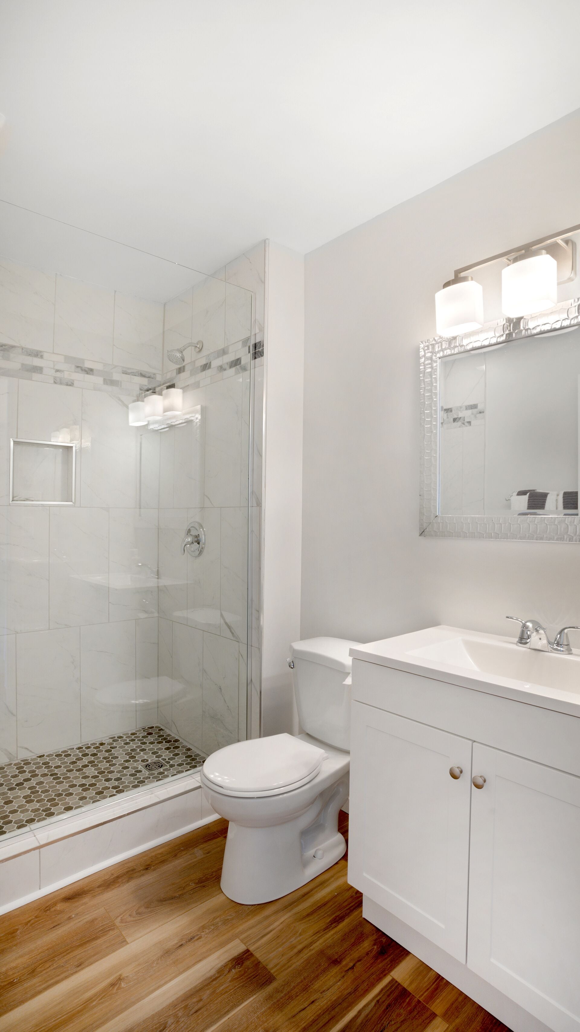 Un baño con ducha de vidrio, inodoro y lavabo con espejo.
