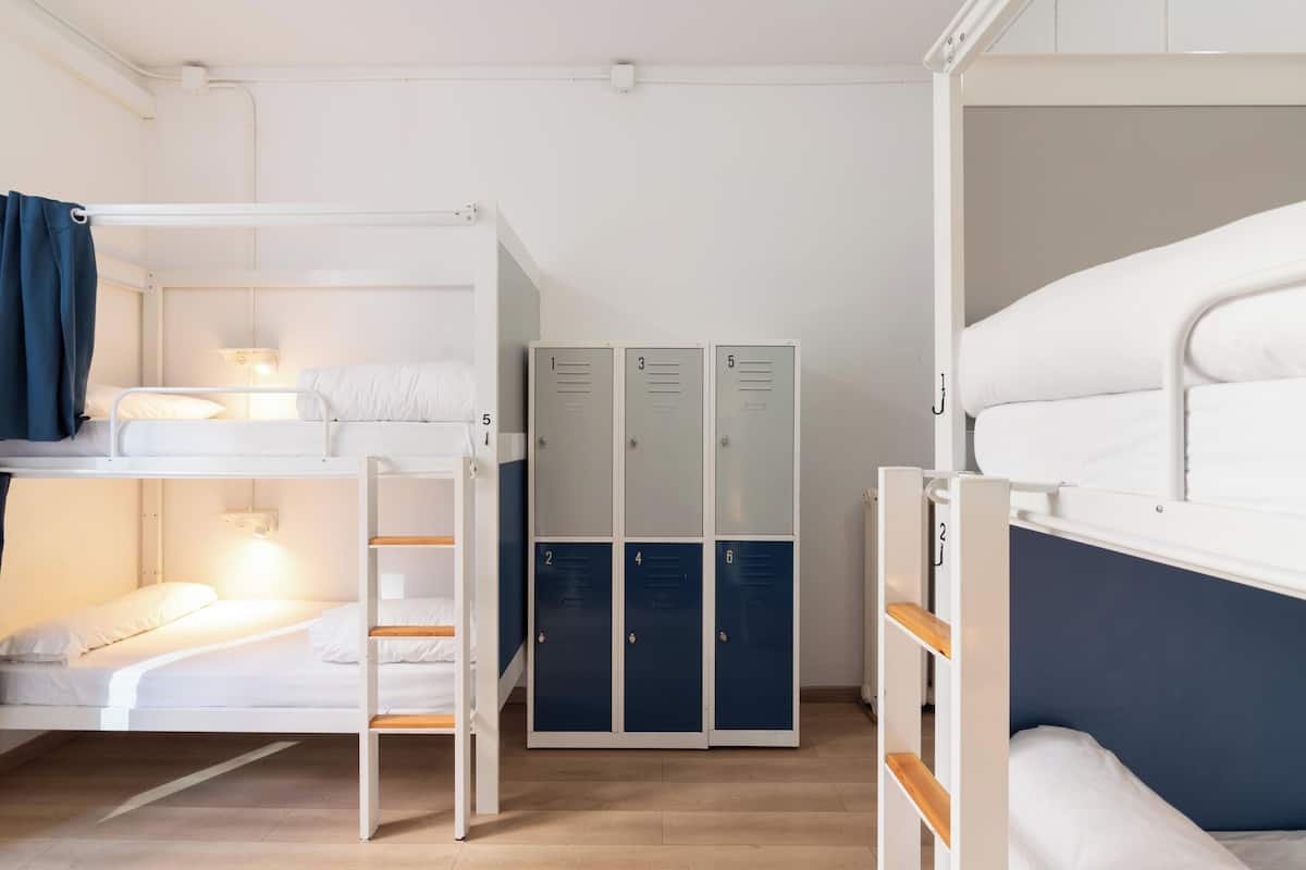 A bunk bed room with a desk, a lamp, and a set of lockers.