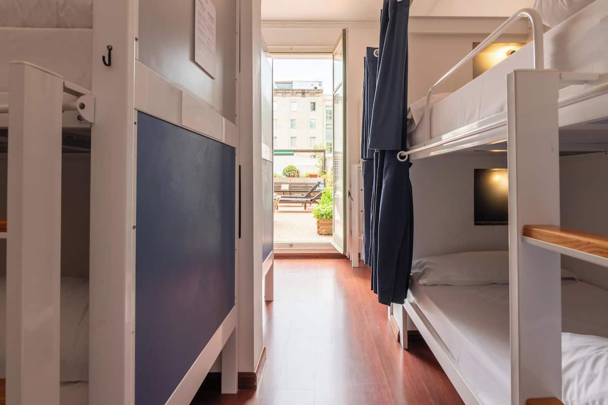 A narrow hallway with bunk beds on one side and a door leading to a balcony.