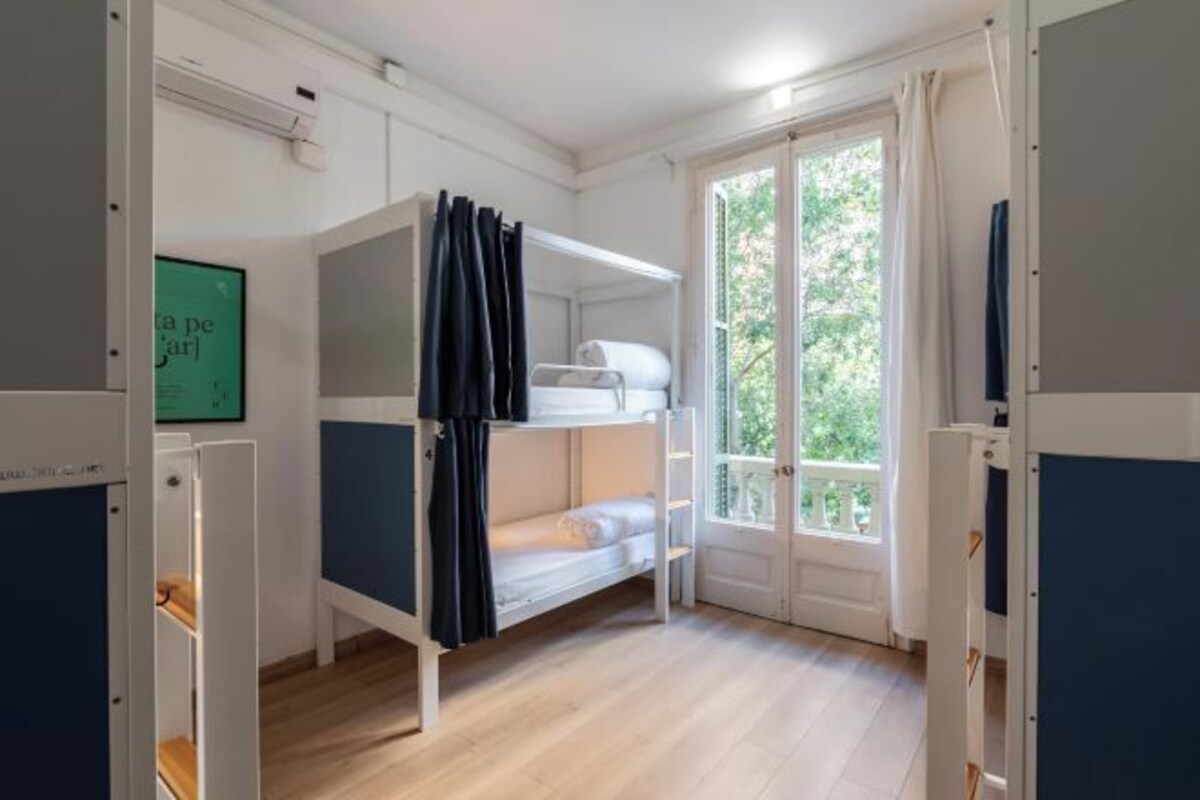 Une chambre avec un lit superposé, une fenêtre, une porte et un tableau encadré au mur.