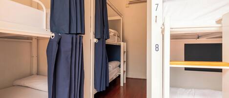 A dormitory room with bunk beds, numbered 7 and 8, and a wooden floor.