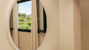Ein rundes Fenster mit Blick auf Grünflächen und ein Gebäude im Hintergrund.