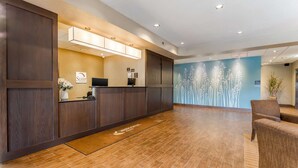 A reception area with a wooden reception desk, a computer, and a wall-mounted sign. - Sleep Inn & Suites Ames near ISU Campus (Ames)
