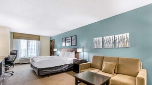A hotel room with a bed, a sofa, a desk, and a chair. There are three framed pictures on the wall. - Sleep Inn & Suites Ames near ISU Campus (Ames)