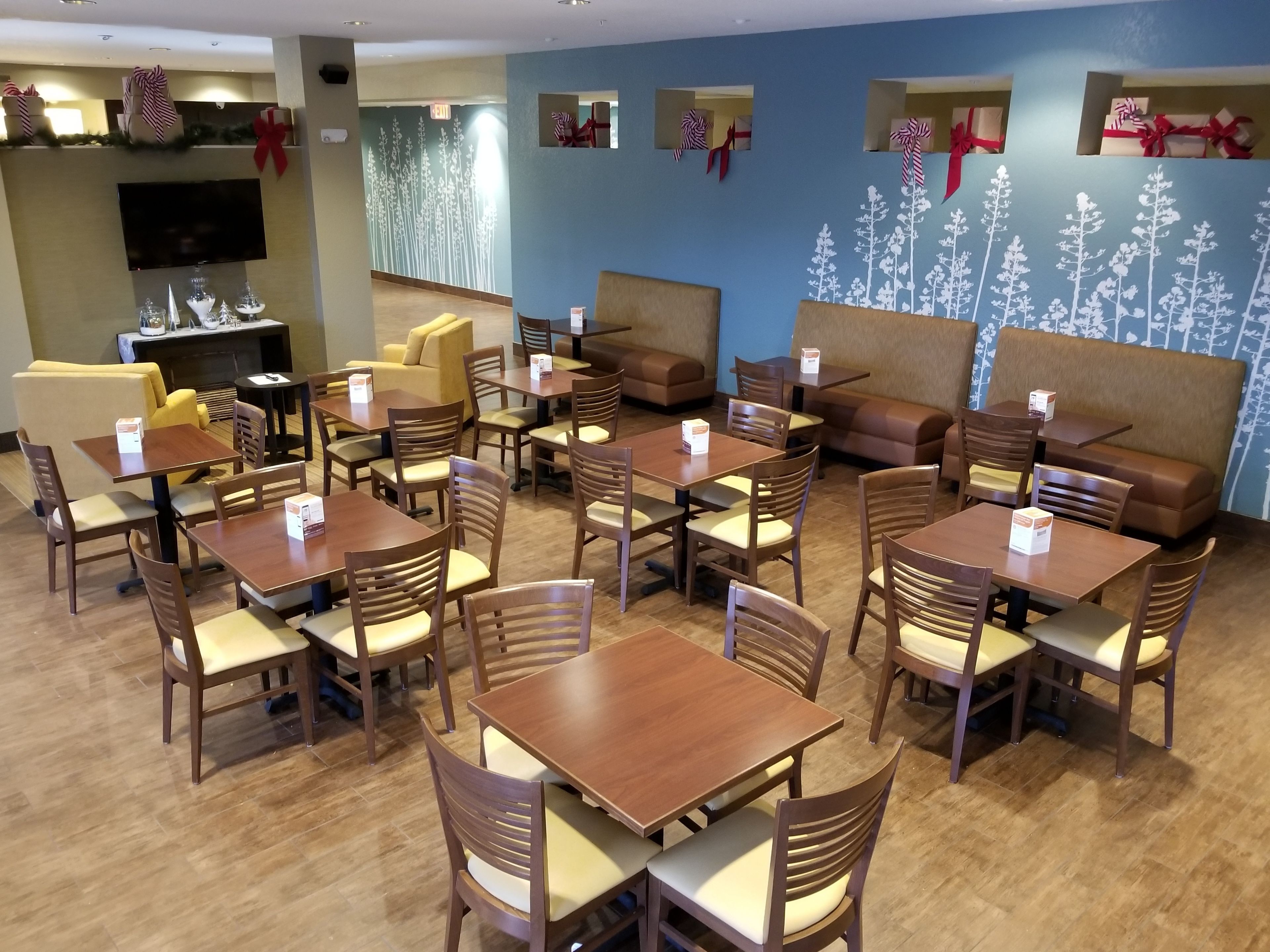 A restaurant with wooden tables and chairs, a fireplace, and Christmas decorations.