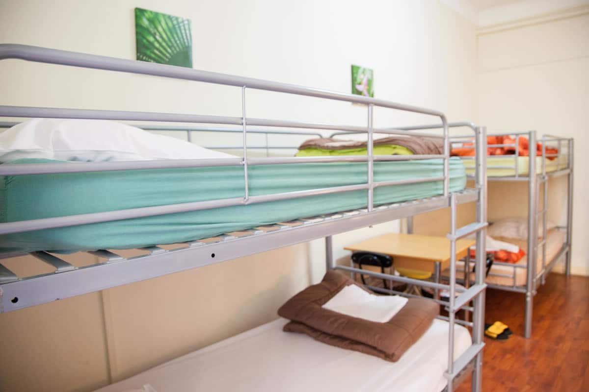 A bunk bed room with metal railings, a desk, and a chair.