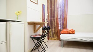 Una habitación pequeña con cama, escritorio, silla y refrigerador.