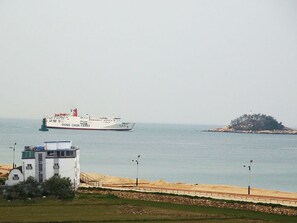 Uma paisagem costeira com um ferry chamado 'DONG CHUN FEARY' e uma pequena ilha ao longe.
