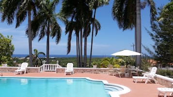 Alberca al aire libre, sombrillas en la alberca y camastros