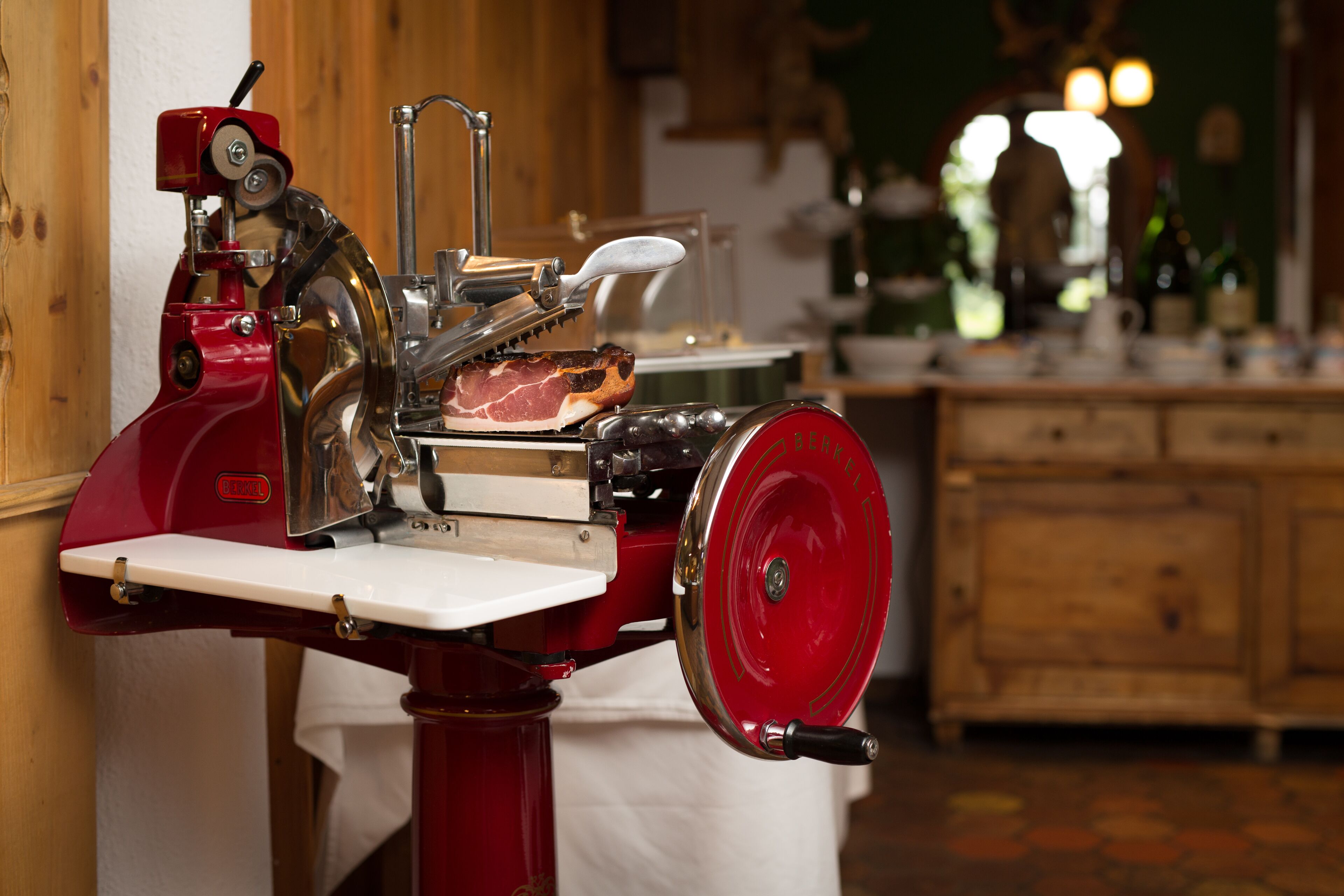Eine Fleischmaschine zum Schneiden von rotem Fleisch in einer Küche mit Holzschränken und einer weißen Arbeitsplatte.
