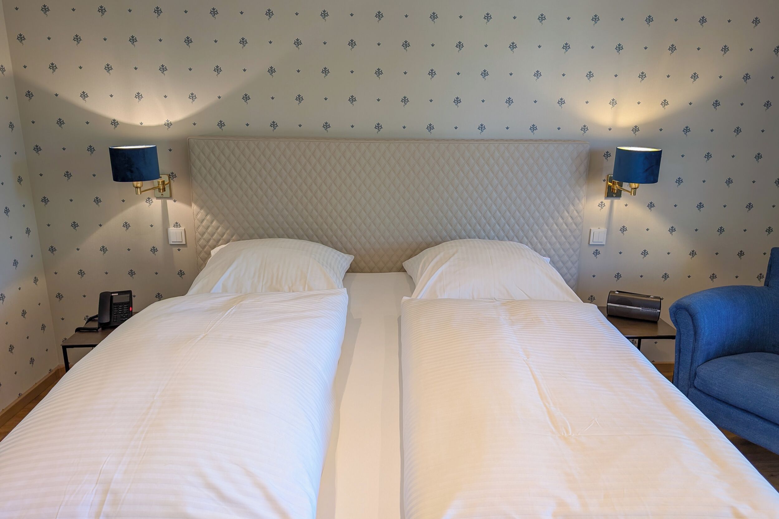 A double bed with white linens, two bedside lamps, and a telephone on the nightstand.
