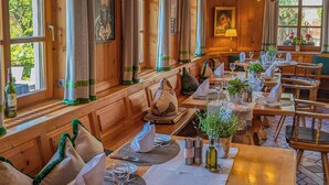 A restaurant with wooden interiors, long tables, and hanging light fixtures.