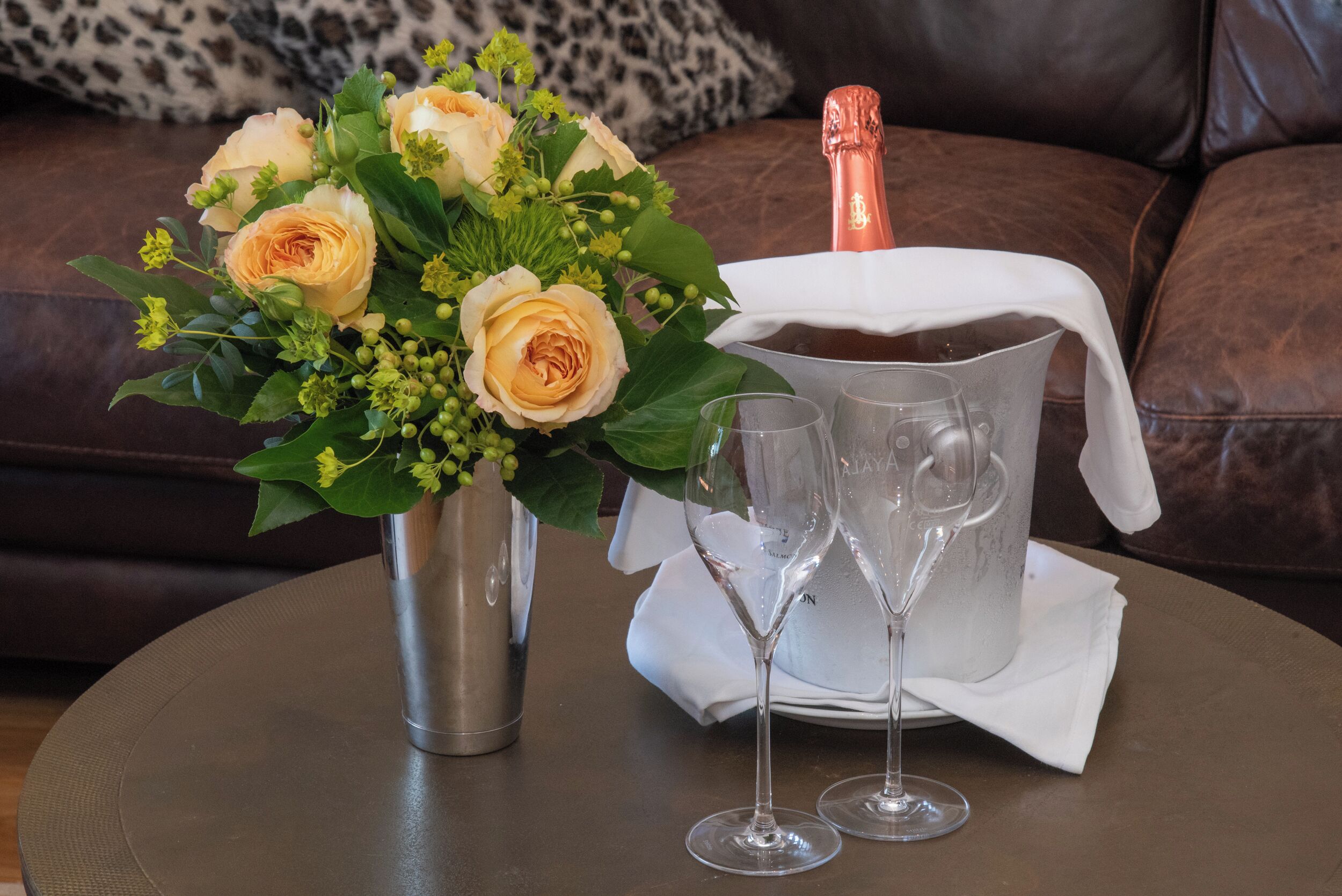 Una mesa con una botella de champán, dos copas y un ramo de flores.