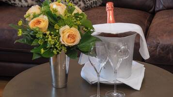 Una mesa con una botella de champán, dos copas y un ramo de flores.